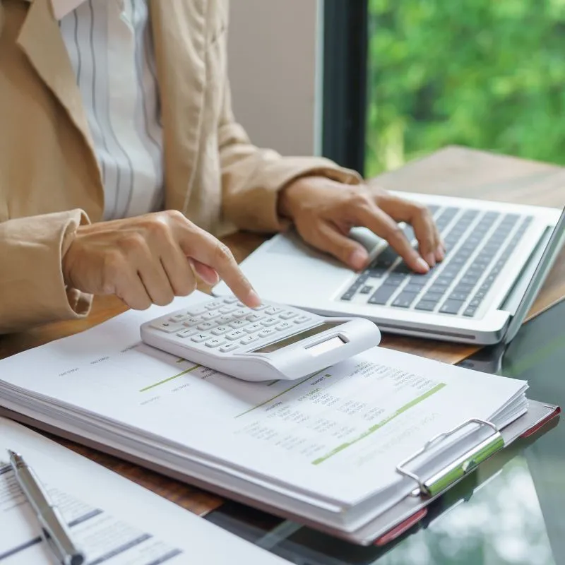 Pelaku UMKM menghitung ongkir menggunakan kalkulator dan laptop untuk pengiriman barang ke Makassar.