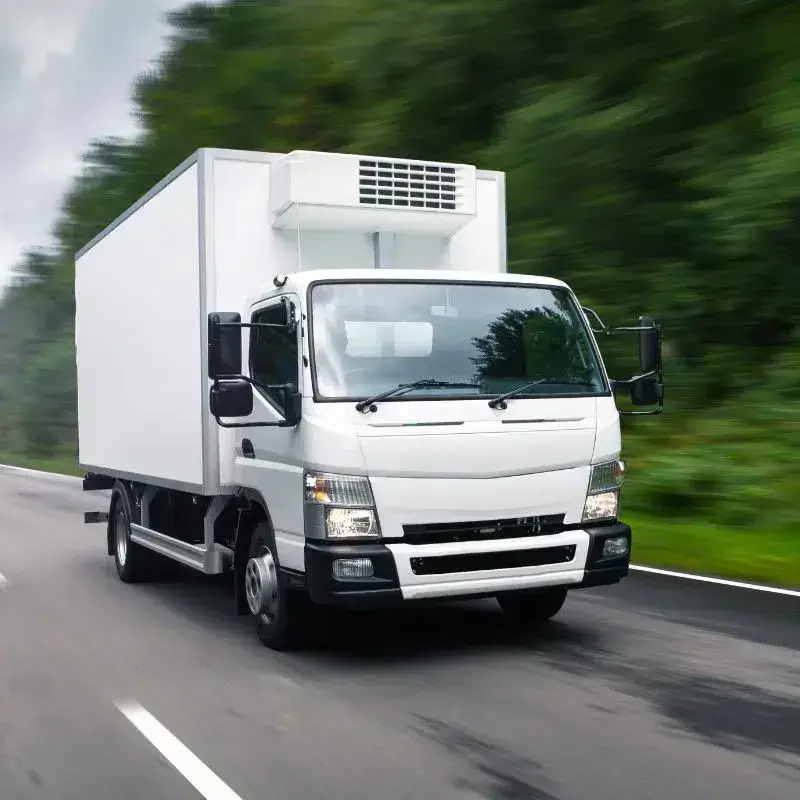 Truk pendingin melaju di jalan sebagai ilustrasi operasional cold chain logistic untuk barang sensitif suhu.