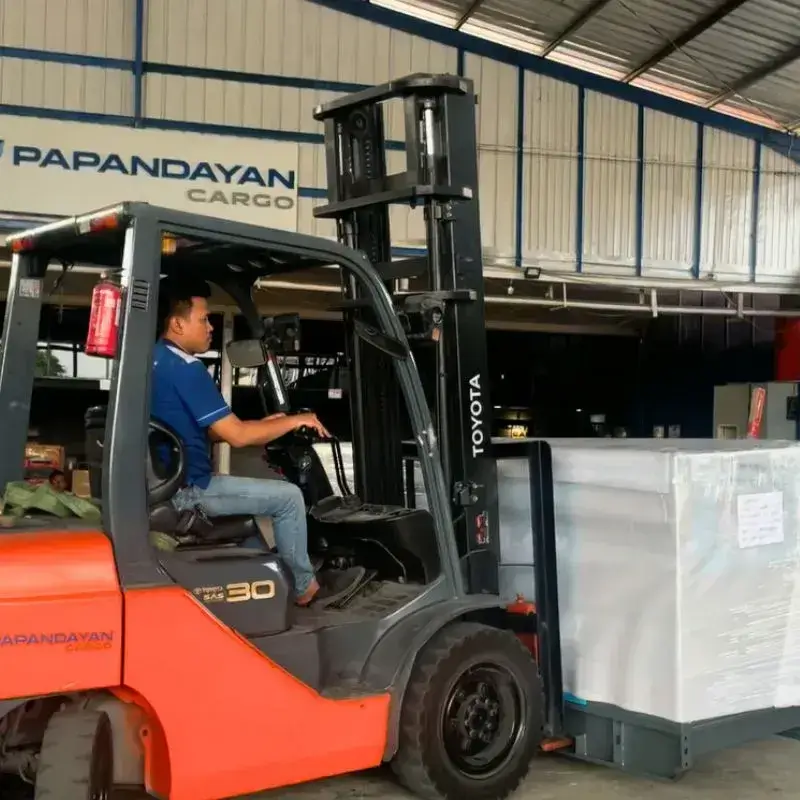 Operator forklift mengangkat mesin berat terpacking sebagai ilustrasi proses packing mesin berat.