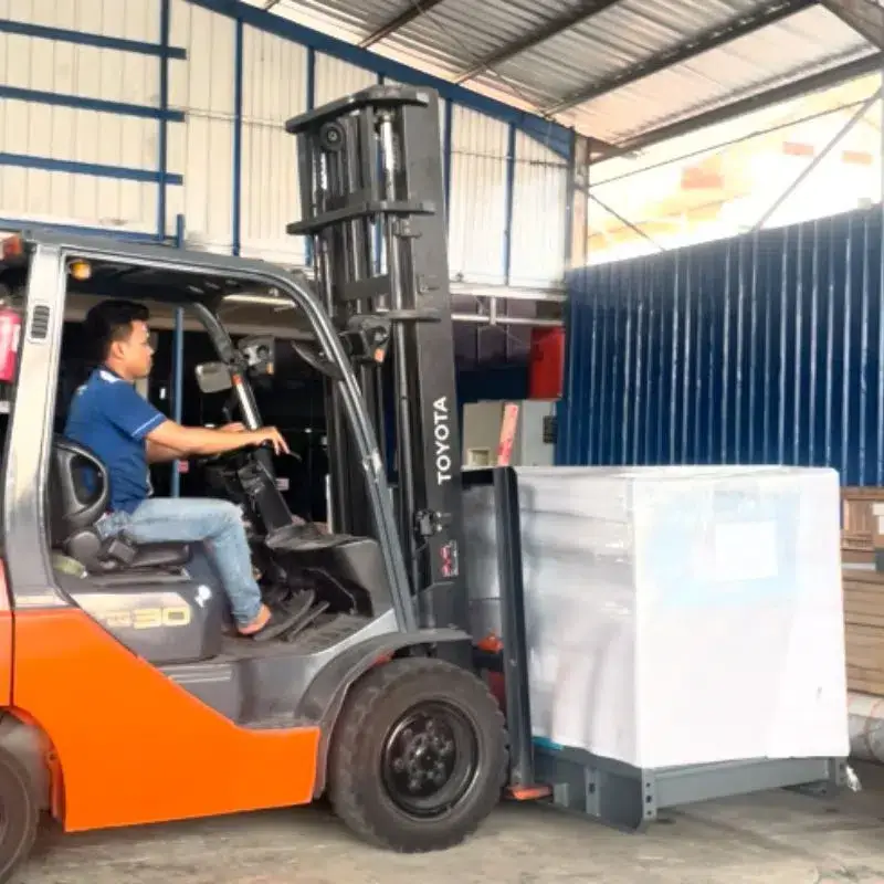 Forklift mengangkat mesin terpacking sebagai ilustrasi Kirim mesin usaha ke Makassar.