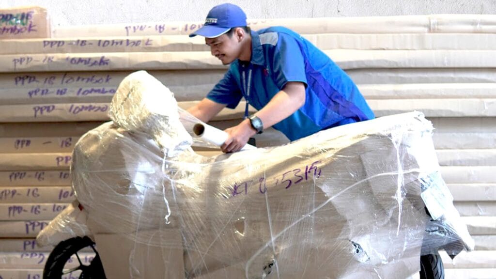 Petugas melakukan wrapping motor sebagai bagian dari layanan pengemasan & POD kembali papandayan cargo yang terstandar.