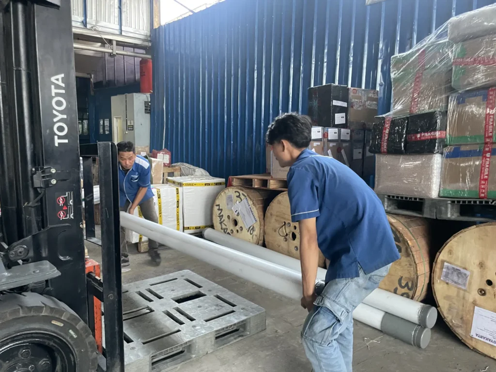 Staff logistik Papandayan Cargo menangani barang panjang di gudang dengan bantuan forklift sebelum proses pengiriman